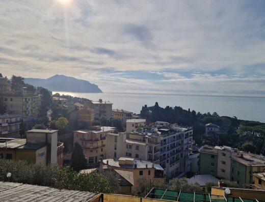 Vista panoramica mozzafiato sull'Agriturismo Le Pale, con case colorate che si affacciano sul mare scintillante sotto un cielo nuvoloso e soleggiato.