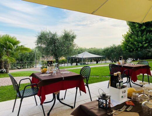 Tavoli apparecchiati all'aperto all'Agriturismo Le Tese, con vista sul giardino e sulla campagna circostante.