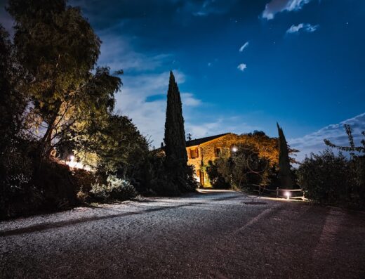 Agriturismo Le Valli di notte: paesaggio illuminato con cielo stellato, vegetazione lussureggiante e costruzione tipica toscana, ideale per vacanze e relax.