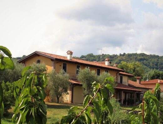 Agriturismo L'Oro Rosso: Esterno della struttura con giardino e vegetazione circostante, tipica casa colonica italiana con tetto in tegole rosse.