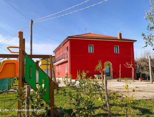 Agriturismo Macchia dei Briganti: vista esterna della struttura con area giochi per bambini in primo piano, ideale per famiglie in vacanza.