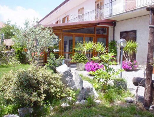 Agriturismo Mare e Monti: Veduta esterna della struttura con giardino curato, piante ornamentali e dettagli rustici. Ideale per una vacanza rilassante nella natura.