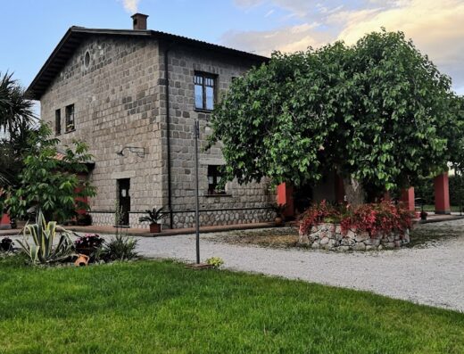 Agriturismo Masseria Campierti: Exterior view of the stone building with lush greenery and gravel driveway in Puglia, Italy.
