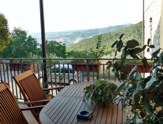 Terrazza panoramica all'Agriturismo Masseria Pinto con tavolo in legno, sedie e vista sulle colline circostanti. Ideale per relax e vacanze in Puglia.