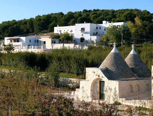 Agriturismo Masseria Torricella, Puglia: vista esterna della masseria bianca e dei trulli tipici in un paesaggio rurale.
