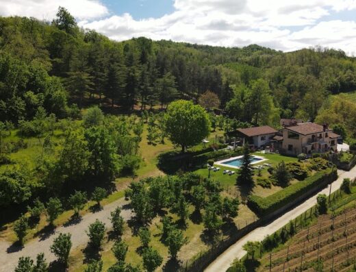 Vista aerea dell'Agriturismo Nonna Du, immerso nel verde delle colline italiane, con piscina, vigneto e vegetazione lussureggiante.