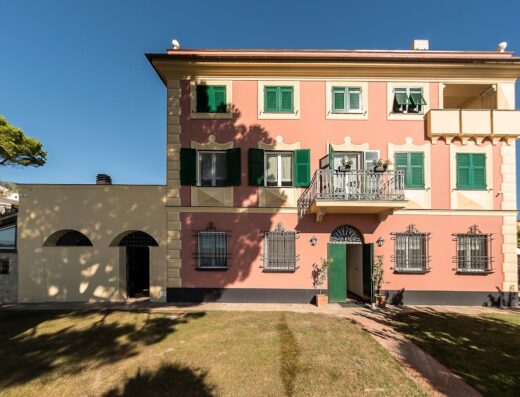 Agriturismo Olivenere: Charming Italian villa with pink facade, green shutters, and a balcony, set in a lush green lawn, ideal for a relaxing vacation in the countryside.