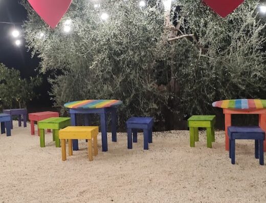 Tavoli e sedie colorate all'aperto presso Agriturismo Passione Natura, perfetti per degustazioni di prodotti tipici in un'atmosfera accogliente.