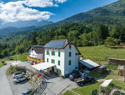 Agriturismo Plan Da Crosc, incantevole vista aerea sulla struttura con pannelli solari, circondata da montagne verdi, ideale per vacanze rilassanti.