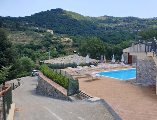 Agriturismo Ponte Due Archi: Piscina con lettini e ombrelloni, circondata da colline verdi, ideale per un soggiorno rilassante in Italia.