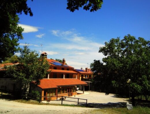 Agriturismo Radovič: Esterno della struttura con cielo azzurro, tetto rosso e vegetazione circostante, ideale per motociclisti in viaggio.