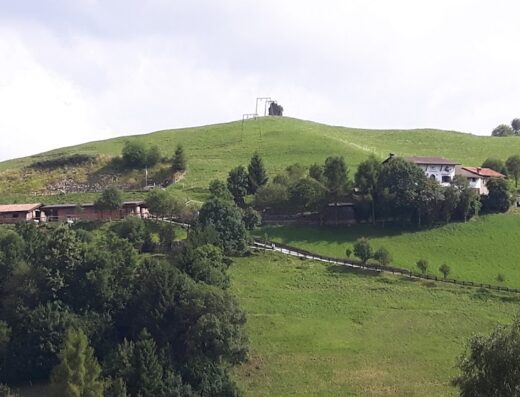 Scenic view of Agriturismo Ranch Vaghezza Gilberto nestled on a green hill, with stables and a farmhouse visible among the trees, offering a serene travel destination.