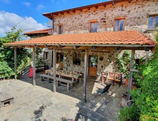 Agriturismo Risveglio Naturale a Varese Ligure: vista esterna della struttura in pietra con tavolo apparecchiato sotto il portico