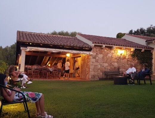 Agriturismo Sa Mendhula: View of guests relaxing on the lawn and patio of the agriturismo at dusk, enjoying the outdoor space and ambiance.