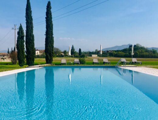 Piscina azzurra dell'Agriturismo Sambuco con lettini prendisole e vista panoramica sulle colline toscane, ideale per relax e vacanze all'insegna della natura.