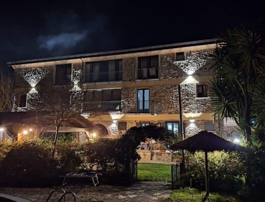 Agriturismo San Basilio at night, showcasing the illuminated stone building, garden entrance, and outdoor seating area.