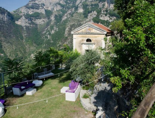 Agriturismo Sant'Alfonso: Scenic view of outdoor seating area with lounge furniture, overlooking mountains and an old building in Italy.
