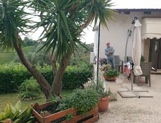 Agriturismo Stelle Invadenti: Vista esterna con giardino curato, vegetazione rigogliosa, zona relax e persona in piedi che si gode la tranquillità del luogo. Un'oasi ideale per motociclisti in viaggio.