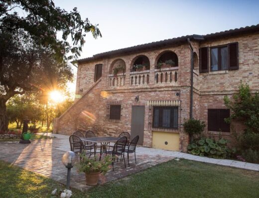 Agriturismo Terralieta: Scorcio esterno della struttura in mattoni rossi con tavolo e sedie da giardino per gli ospiti.