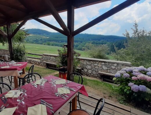Ristorante all'aperto con vista panoramica sulla Valle del Salto, tavoli apparecchiati e fiori. Cucina tipica e atmosfera rilassante.