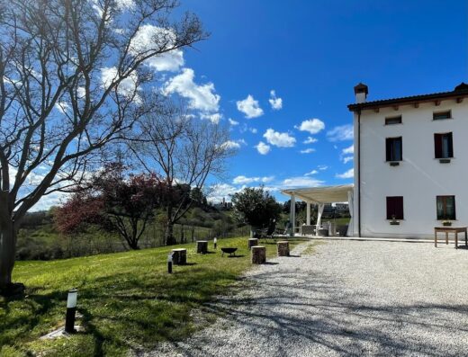 Agriturismo Vecio Portico: vista esterna della struttura con prato verde, alberi, e cielo azzurro, ideale per un soggiorno rilassante.
