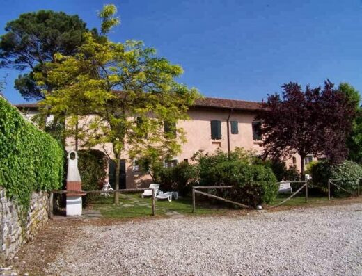 Agriturismo Villa Coren: View of the villa's exterior with stone wall, trees, gravel driveway, and lawn chairs in the garden.