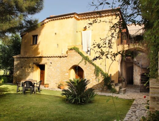 Agriturismo Villa Vittoria: Esterno in pietra con prato verde, tavolo e sedie, ideale per relax e vacanze in agriturismo.