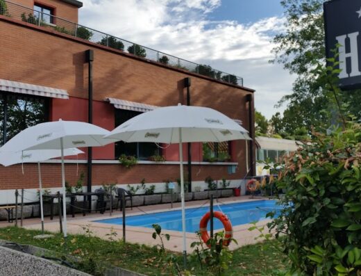 Airone Hotel: Vista della piscina esterna con ombrelloni bianchi e un salvagente arancione, ideale per relax e vacanze.