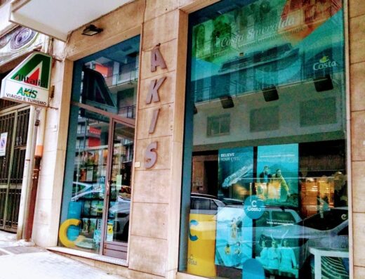 Vetrine dell'agenzia Akis Viaggi s.r.l. con insegne Alitalia e pubblicità di Costa Crociere, offerte viaggi e turismo.