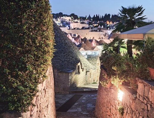 Veduta notturna di Alberobello, Puglia, Italia, con i caratteristici trulli illuminati e stradine in pietra, meta turistica popolare.