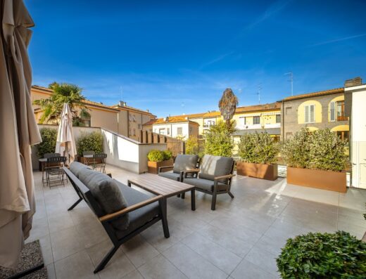 Terrazza panoramica dell'Albergo del Cuore con divano, poltrone, tavolino e piante ornamentali sotto un cielo azzurro.