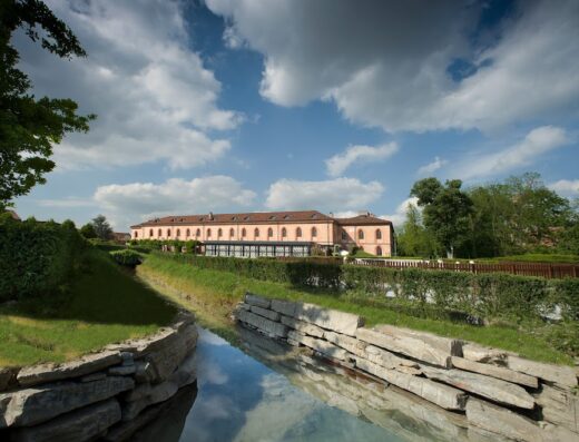 Albergo dell'Agenzia: Vista esterna dell'hotel con riflesso nel canale. Architettura elegante, giardini curati e cielo azzurro.