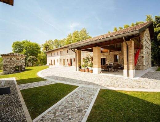Albergo Due Fiumi: Esterno in pietra con vialetto acciottolato, prato curato e portico con tavolo e sedie. Architettura tipica per un soggiorno rilassante.
