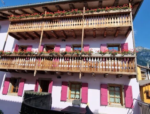 Albergo Grimani, incantevole hotel in stile alpino con balconi fioriti e persiane rosa, ideale per un soggiorno rilassante e una vacanza indimenticabile.
