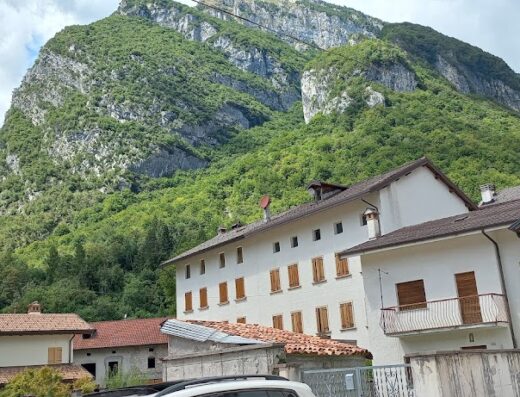 Albergo Ristorante Alla Rosa nestled in the Italian Alps, featuring traditional architecture against a backdrop of lush green mountains.
