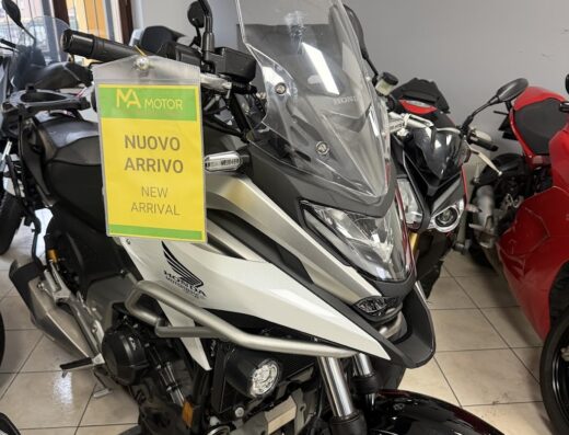 Moto Honda da turismo in esposizione presso Aldus Moto, con cartello "Nuovo Arrivo". Ideale per viaggi e avventure su due ruote. Accessori e servizi disponibili.