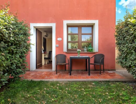 Esterno di una camera dell'Alghero Resort Country Hotel con tavolo, sedie, finestra e porta d'ingresso, ideale per un soggiorno rilassante.