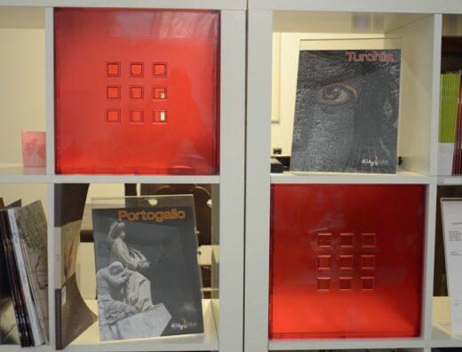 Scaffale bianco con cataloghi di viaggio di Allegro T.O. di Avesta Srl: Portogallo, Turchia e contenitori rossi decorativi. Offerte viaggi e pacchetti turistici.