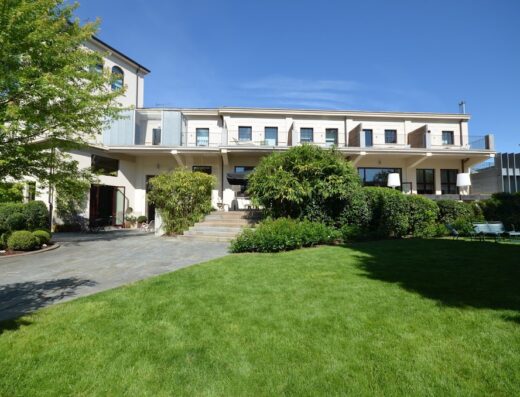 Vista esterna dell'Alter Hotel, con prato verde curato, vialetto in pietra e facciata elegante dell'edificio principale.