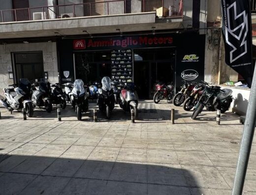 Ammiraglio Motors dealership showcasing a variety of Peugeot, KL, and Mondial motorcycles parked outside the store, highlighting their scooter and motorbike models.