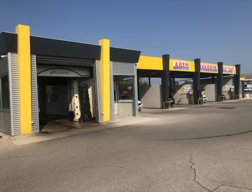 Autolavaggio self-service con diverse postazioni per la pulizia di moto e auto, ideale per motociclisti in viaggio che necessitano di un servizio rapido di lavaggio.