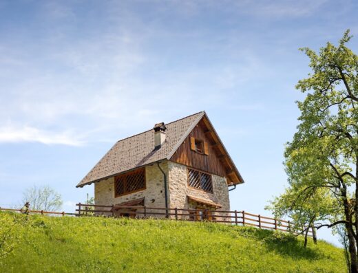 Appartamenti Vacanza Ravascletto Comeglians: Casa vacanze in pietra e legno con tetto spiovente immersa nel verde, ideale per un soggiorno rilassante.