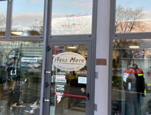 Area Moto: negozio di accessori e abbigliamento moto. Vetrina con caschi, stivali, giacche. Tappeto Nolan X-lite Grex. Rivenditore Airoh, Sena, Spidi, Fox e altri marchi.