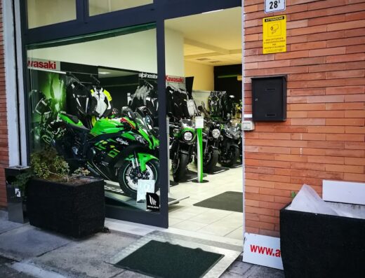 Area Moto Modena: vetrina del negozio con moto Kawasaki Ninja verde in esposizione e abbigliamento tecnico da motociclista.