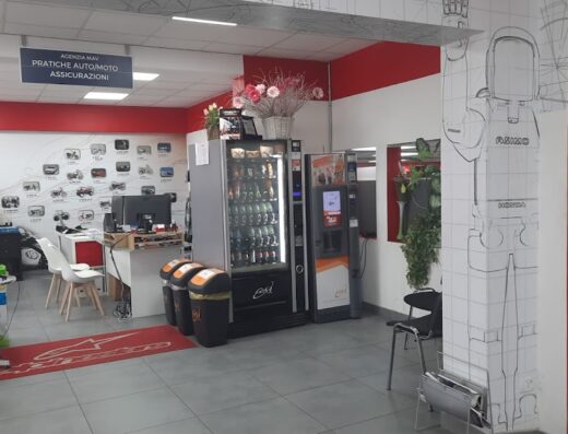 Interior view of Aroni Moto store, featuring a service desk, vending machines, motorcycle insurance signage, and motorcycle-themed wall decorations.
