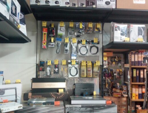 Interno di un negozio di accessori audio per auto e moto, con scaffali pieni di amplificatori, altoparlanti e cavi.