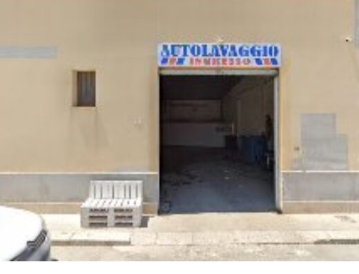 Foto di un autolavaggio con insegna 'AUTOLAVAGGIO INGRESSO', ideale per la pulizia di moto e auto, situato in un'area di servizio.