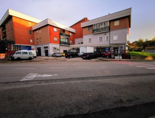 Area di autolavaggio a mano Ifaroni con vari veicoli parcheggiati di fronte all'edificio e segnaletica orizzontale visibile.