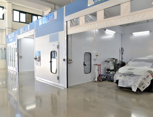 Interno dell'Autocarrozzeria De Luca, con cabine di verniciatura Verta e auto in preparazione per la verniciatura.