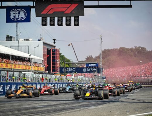 Autodromo Enzo e Dino Ferrari racetrack with Formula 1 race cars lined up at the starting grid, packed grandstands, and FIA signage.